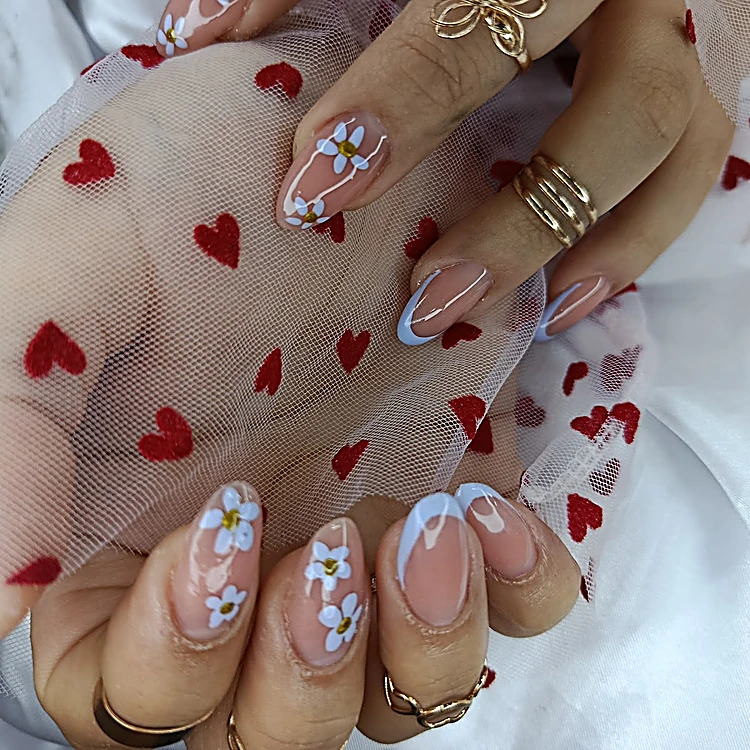 Uñas almendradas con flores azules sobre tul blanco con corazones rojos