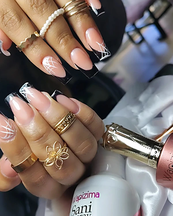 Uñas largas en francés negro con líneas blancas de telaraña y anillos dorados